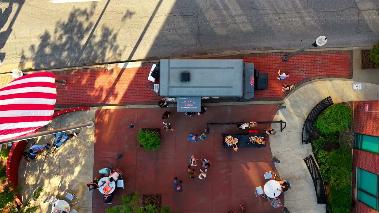 Overhead drone view of a community gathering on a brick plaza at golden hour, filmed by Horizon Heights Productions.