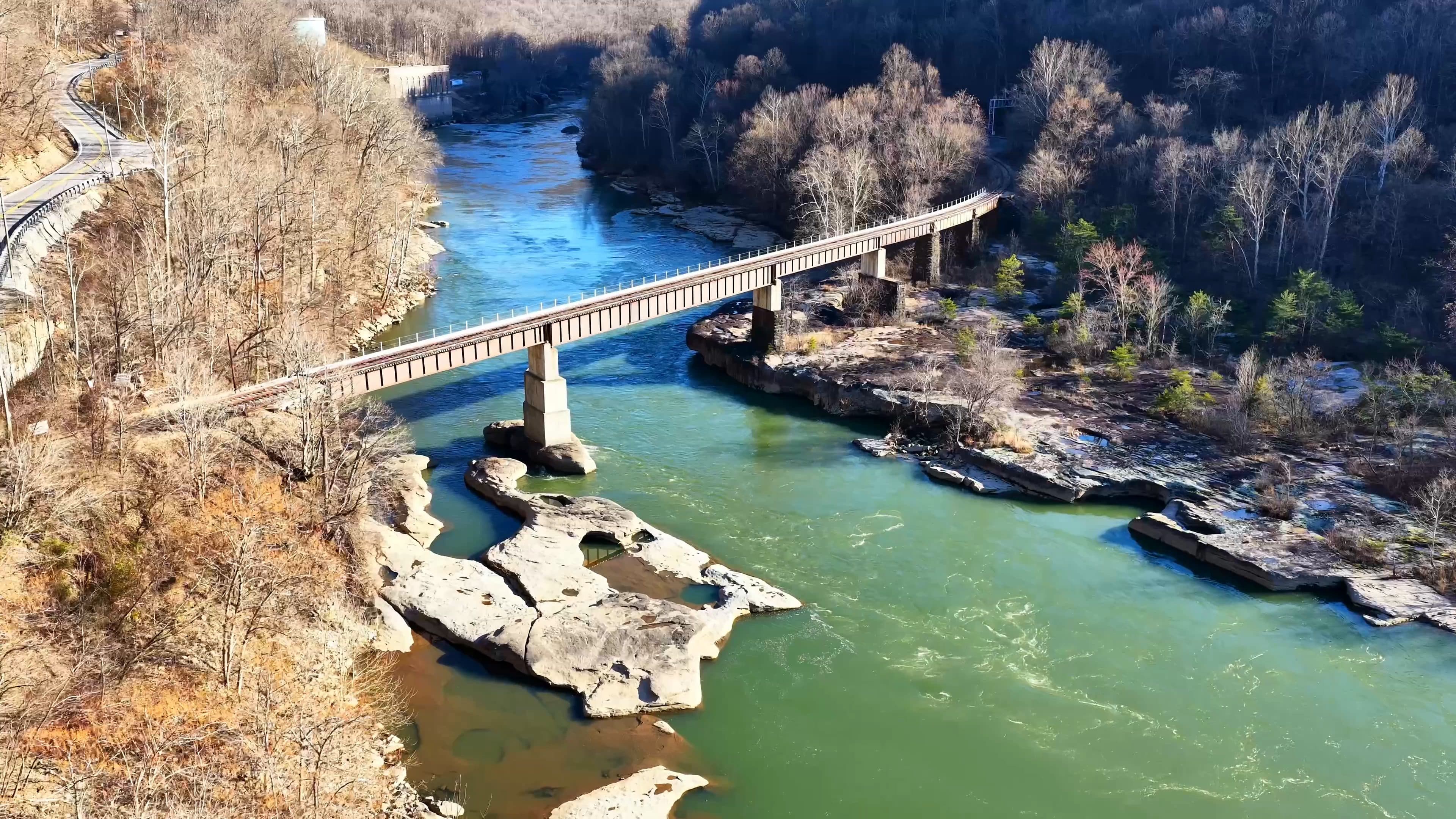 Drone view of a bridge spanning a turquoise river through a rocky gorge, by Horizon Heights Productions.