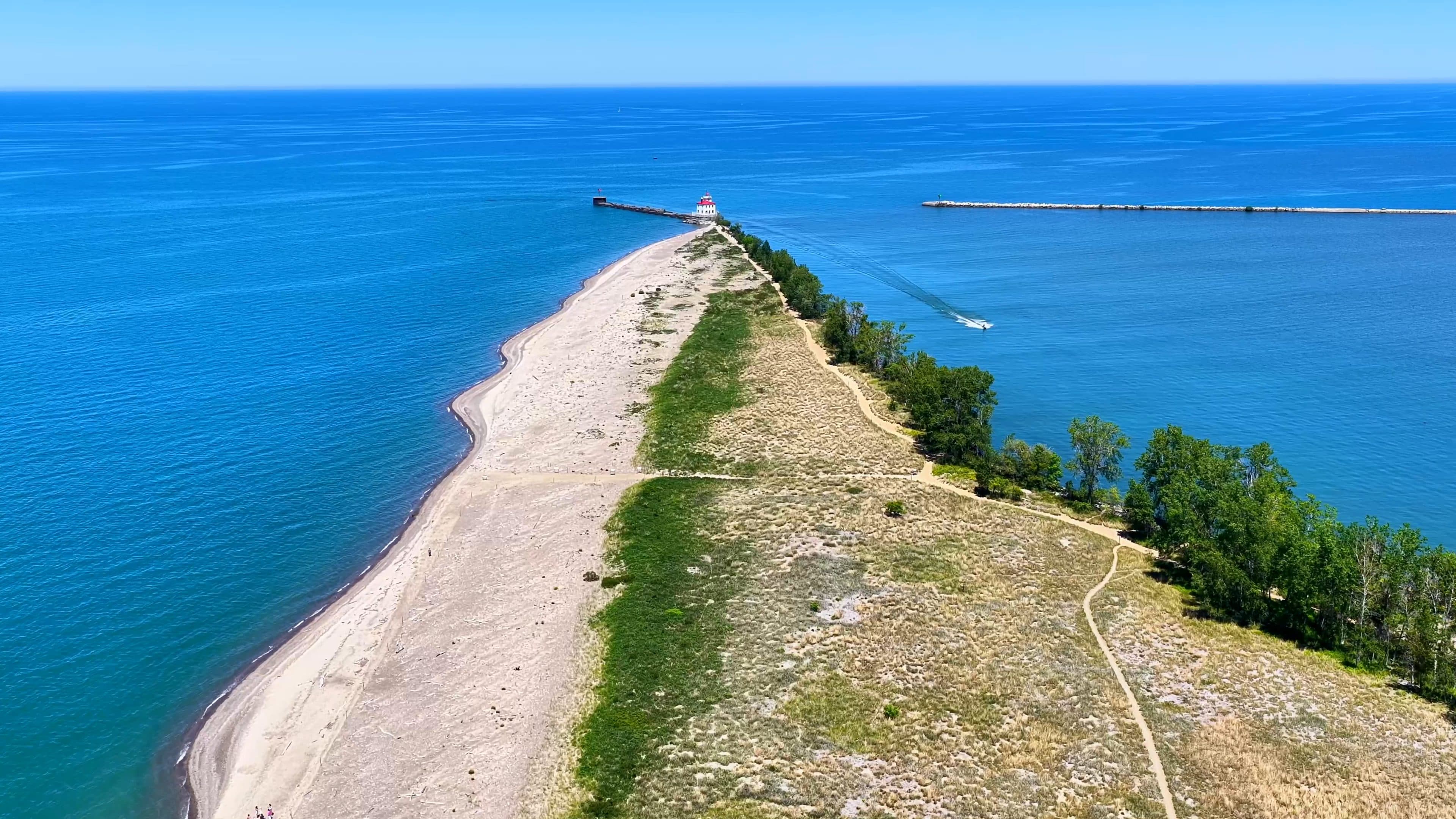 Aerial view of a sandy shoreline spit reaching into a Great Lake, by Horizon Heights Productions.