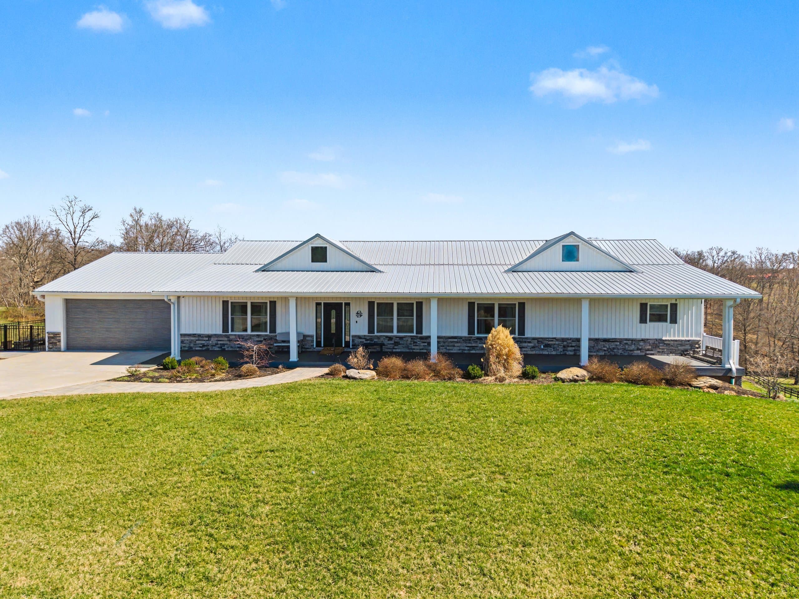 Aerial drone photograph of the 109 Clare Kennedy Drive ranch-style home with metal roof, stone accents, and wraparound porch in Marietta, Ohio by Horizon Heights Productions.